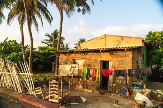 View of a modest weathered stone house with laundry hanging on a line and palm trees under a clear sky in Galle Southern Province Sri Lanka.