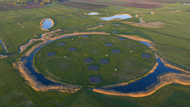 Aerial view of the LOFAR superterp radio telescope station featuring circular antenna arrays on a green island surrounded by water and lush fields Buinen Drenthe Netherlands. Aerial view of the LOFAR superterp radio telescope station featuring circular antenna arrays on a green island surrounded by water and lush fields Buinen Drenthe Netherlands.