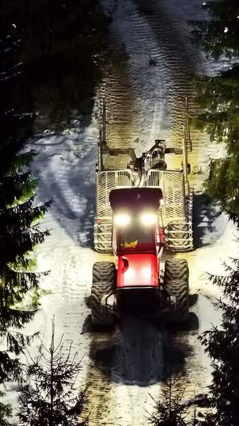 Aerial view of forestry machine in snowy forest Latvia.