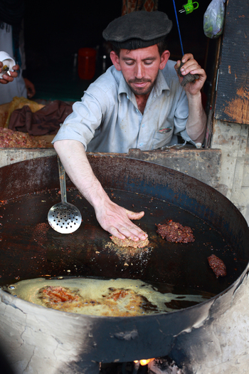 Chitral Khyber Pakhtunkhwa Pakistan 18 May 2013 View of a man cooking traditional meat patties in a large pan at a food shop in the bazaar.