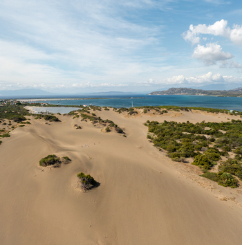 Aerial view of the sand dunes at Las Calderas with lush green vegetation and the blue waters of the bay under a clear sky in Bani Peravia Dominican Republic.