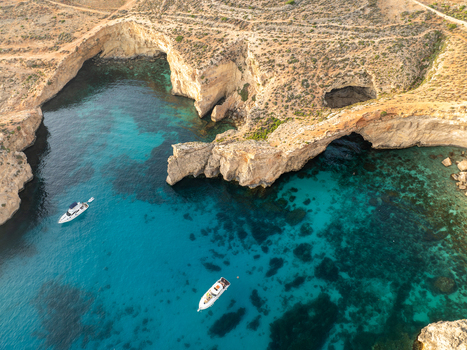 Aerial view of the turquoise waters meeting the rugged coastline at the Blue Lagoon a picturesque scene with boats gently floating Blue lagoon Comino Malta. Aerial view of the turquoise waters meeting the rugged coastline at the Blue Lagoon a picturesque scene with boats gently floating Blue lagoon Comino Malta.
