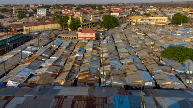Aerial view of the central market featuring rows of corrugated metal roofs surrounding urban buildings and infrastructure in Tamale Northern Region Ghana. Aerial view of the central market featuring rows of corrugated metal roofs surrounding urban buildings and infrastructure in Tamale Northern Region Ghana.