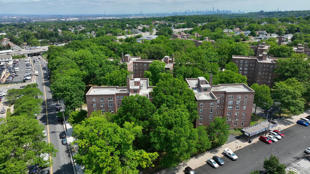 Aerial view of Staten Island Greenbelt featuring lush trees surrounding residential brick apartment buildings with a distant city skyline in New York New York United States.