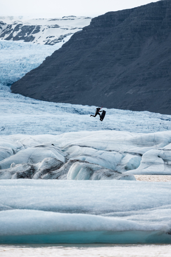 View of a kiteboarder jumping in the air in front of the massive Vatnajokull glacier in Iceland.