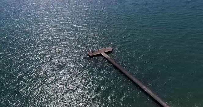 Aerial view of a long pier extending into the blue sea Italy.