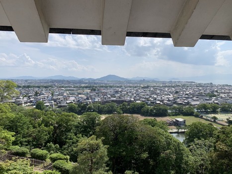 Japan 06 July 2026 View of a Japanese town with traditional rooftops lush green trees and distant mountains under a blue sky. Japan 06 July 2026 View of a Japanese town with traditional rooftops lush green trees and distant mountains under a blue sky.