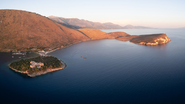 Aerial view of Porto Palermo Castle on a peninsula surrounded by blue waters and rugged mountains at sunset near Palermo Beach Himare Vlore County Albania. Aerial view of Porto Palermo Castle on a peninsula surrounded by blue waters and rugged mountains at sunset near Palermo Beach Himare Vlore County Albania.
