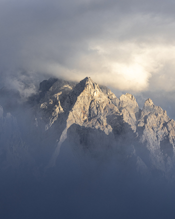 View of rocky mountain peaks piercing through swirling clouds bathed in soft sunlight a serene natural vista Picos de Europa Asturias Spain. View of rocky mountain peaks piercing through swirling clouds bathed in soft sunlight a serene natural vista Picos de Europa Asturias Spain.