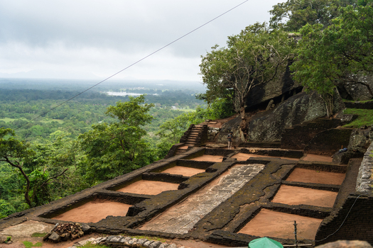View of the ancient stone foundations and ruins of Sigiriya rock fortress overlooking the lush tropical jungle under an overcast sky Sigiriya Central Province Sri Lanka. View of the ancient stone foundations and ruins of Sigiriya rock fortress overlooking the lush tropical jungle under an overcast sky Sigiriya Central Province Sri Lanka.