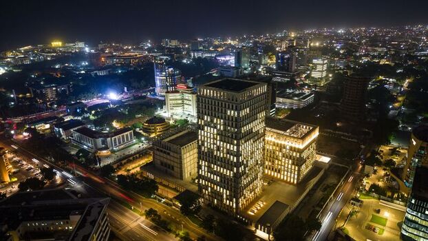 Aerial view of a modern illuminated high rise building complex surrounded by the vibrant city lights of Accra Ghana.
