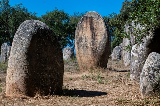 View of the ancient standing stones at Almendres Cromlech set in a grassy field under a clear blue sky in Nossa Senhora de Guadalupe Distrito de Evora Portugal. View of the ancient standing stones at Almendres Cromlech set in a grassy field under a clear blue sky in Nossa Senhora de Guadalupe Distrito de Evora Portugal.