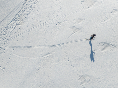 Aerial view of a lone skier trekking across the pristine snow covered south slope of Mount Etna with long shadows and tracks on the white surface Nicolosi Sicilia Italy. Aerial view of a lone skier trekking across the pristine snow covered south slope of Mount Etna with long shadows and tracks on the white surface Nicolosi Sicilia Italy.