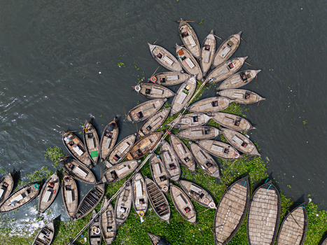 Aerial view of traditional wooden boats clustered on the Buriganga River with fishermen and green water hyacinths in Dhaka Dhaka Division Bangladesh.