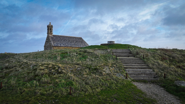 Aerial view of the Mont Saint Michel de Brasparts chapel standing on a grassy hilltop under a dramatic cloudy sky in Saint Rivoal Bretagne France. Aerial view of the Mont Saint Michel de Brasparts chapel standing on a grassy hilltop under a dramatic cloudy sky in Saint Rivoal Bretagne France.