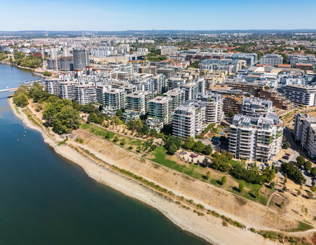 Aerial view of modern apartment buildings and active construction lining the Danube waterfront in the Vizafogo neighborhood of Budapest Hungary with a riverside park and dense urban skyline. Aerial view of modern apartment buildings and active construction lining the Danube waterfront in the Vizafogo neighborhood of Budapest Hungary with a riverside park and dense urban skyline.