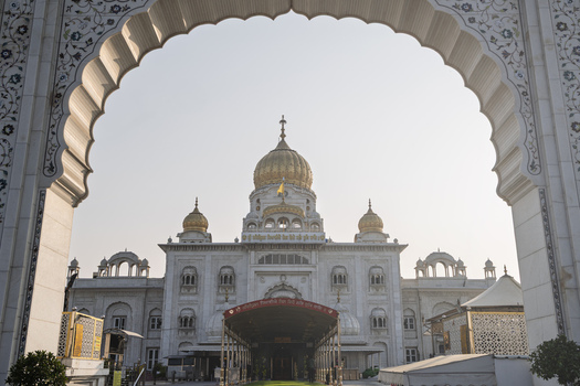 View of the radiant Gurudwara Bangla Sahib framed by a carved archway its golden domes gleaming under the soft light of day a spiritual haven New Delhi Delhi India. View of the radiant Gurudwara Bangla Sahib framed by a carved archway its golden domes gleaming under the soft light of day a spiritual haven New Delhi Delhi India.