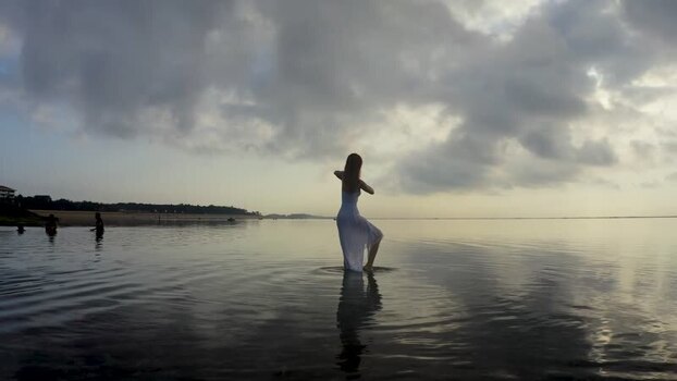Aerial view of a woman in a white dress standing in shallow water Indonesia.