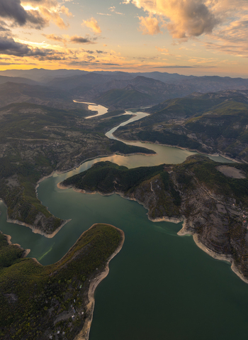 Aerial view of Kardzhali Reservoir winding through lush green hills under a golden sunset sky in Kardzhali Province Bulgaria. Aerial view of Kardzhali Reservoir winding through lush green hills under a golden sunset sky in Kardzhali Province Bulgaria.
