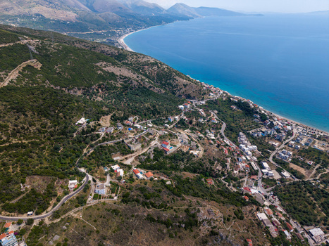Aerial view of the hillside village of Qeparo Fshat with stone houses winding roads and lush greenery overlooking the turquoise Ionian Sea Qeparo Fshat Vlore County Albania. Aerial view of the hillside village of Qeparo Fshat with stone houses winding roads and lush greenery overlooking the turquoise Ionian Sea Qeparo Fshat Vlore County Albania.