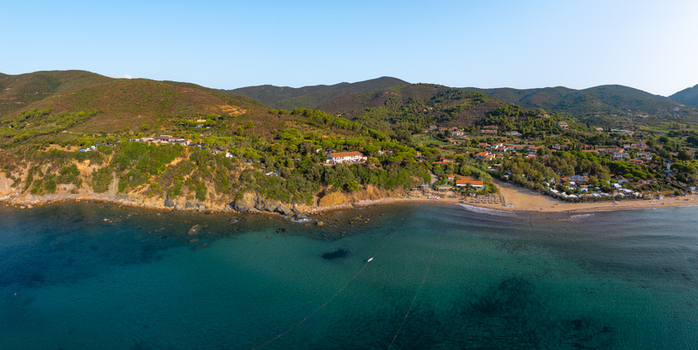 Aerial view of Lacona Beach with turquoise water sandy shoreline and lush green hillsides in Lacona Tuscany Italy.