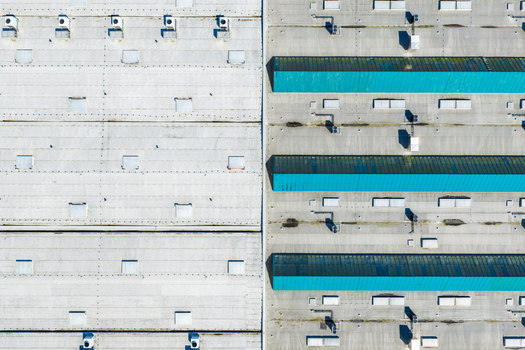 Aerial view of an industrial building roof with grey concrete sections and rows of bright turquoise skylights ventilation units and metal structures in Prague Prague Czechia.
