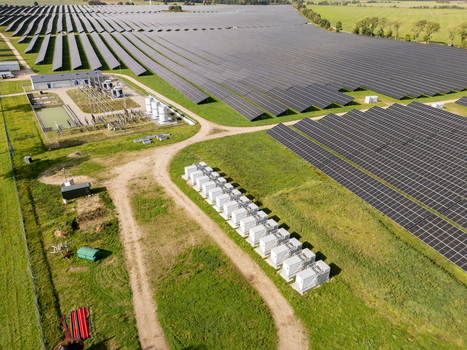 Aerial view of a large scale solar farm featuring rows of photovoltaic panels and a battery energy storage system in the foreground set in a rural landscape in Poland. Aerial view of a large scale solar farm featuring rows of photovoltaic panels and a battery energy storage system in the foreground set in a rural landscape in Poland.