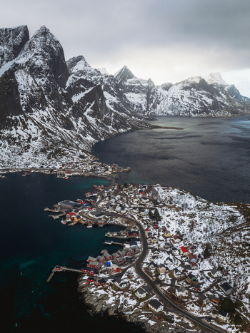 Aerial view of Reinebringen s charming village nestles amidst the stark snow dusted peaks and the serene dark waters Reinebringen Nordland Norway.