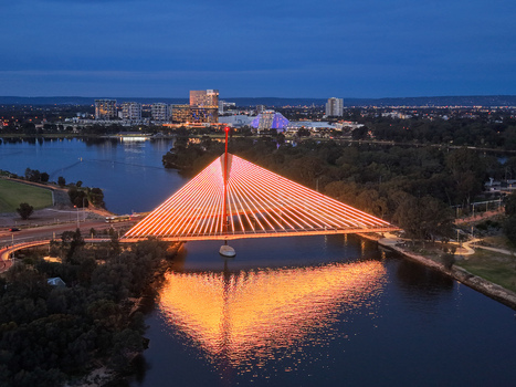 Aerial view of the illuminated Boorloo Bridge spanning the Swan River at night with the city skyline and reflections visible in the water in East Perth Western Australia Australia.