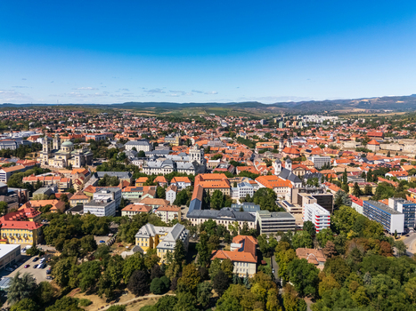Aerial view of Eger city center with the Basilica Eger Castle red roofed historic buildings and tree lined streets against rolling hills in northern Hungary during summer. Aerial view of Eger city center with the Basilica Eger Castle red roofed historic buildings and tree lined streets against rolling hills in northern Hungary during summer.