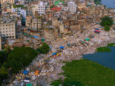 Aerial view of the Buriganga River bank covered in waste next to dense urban housing and makeshift shelters in Keraniganj Dhaka Division Bangladesh. Aerial view of the Buriganga River bank covered in waste next to dense urban housing and makeshift shelters in Keraniganj Dhaka Division Bangladesh.