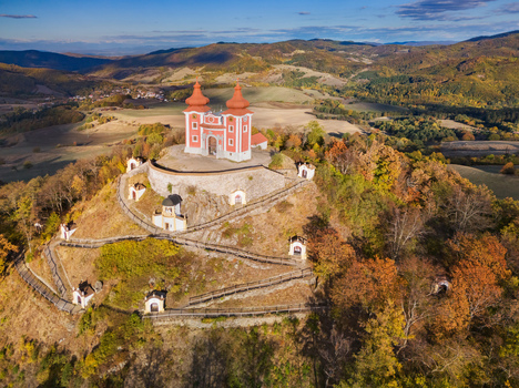 Aerial view of Stiavnicka kalvaria a historic pilgrimage site with a red church and chapels on a hill surrounded by autumn forests in Banska Stiavnica Banskobystricky kraj Slovakia. Aerial view of Stiavnicka kalvaria a historic pilgrimage site with a red church and chapels on a hill surrounded by autumn forests in Banska Stiavnica Banskobystricky kraj Slovakia.