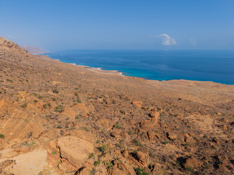 Aerial view of the rugged arid landscape meets the turquoise waters of the coast under a clear sky Erissel Socotra Yemen.