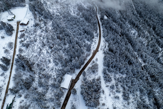 Aerial view of a snow covered forest road winding through a winter landscape with scattered buildings near Mummelsee in Seebach Baden Wurttemberg Germany. Aerial view of a snow covered forest road winding through a winter landscape with scattered buildings near Mummelsee in Seebach Baden Wurttemberg Germany.