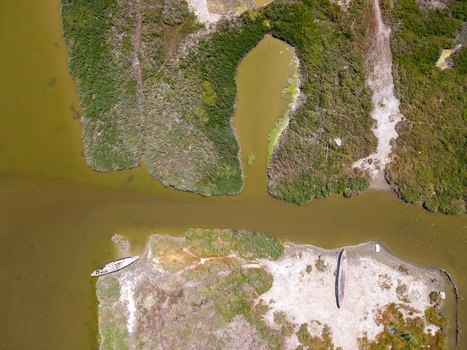 Aerial view of the Vivari Channel featuring marshy wetlands green vegetation and two small boats resting on the sandy banks in Sarande Vlore County Albania.