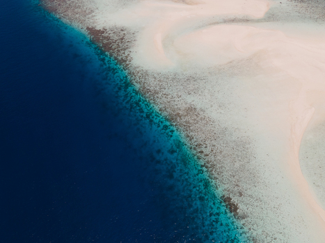 Aerial view of Pasir Timbul Mansuar sandbar surrounded by turquoise coral reefs and deep blue ocean waters in Raja Ampat Papua Barat Indonesia. Aerial view of Pasir Timbul Mansuar sandbar surrounded by turquoise coral reefs and deep blue ocean waters in Raja Ampat Papua Barat Indonesia.