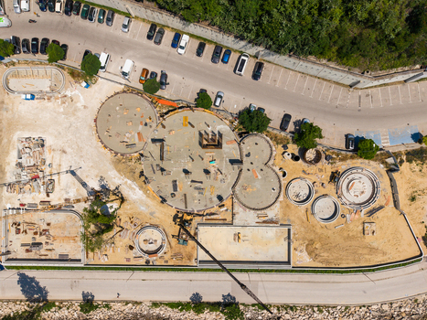 Aerial view of the construction site at Alley First featuring circular concrete foundations a crane and a nearby parking lot in Varna Varna Bulgaria. Aerial view of the construction site at Alley First featuring circular concrete foundations a crane and a nearby parking lot in Varna Varna Bulgaria.
