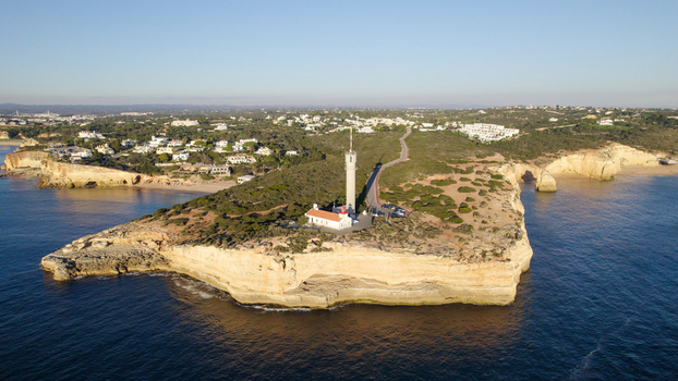 Aerial view of the Ponta do Altar Lighthouse situated on a rocky cliff overlooking the Atlantic Ocean in Ferragudo Faro District Portugal.