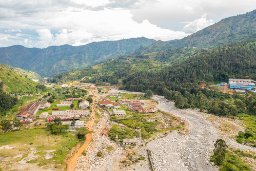 Aerial view of the Kilembe mining area with industrial buildings a dry riverbed and surrounding lush green mountains in Kilembe Western Region Uganda. Aerial view of the Kilembe mining area with industrial buildings a dry riverbed and surrounding lush green mountains in Kilembe Western Region Uganda.