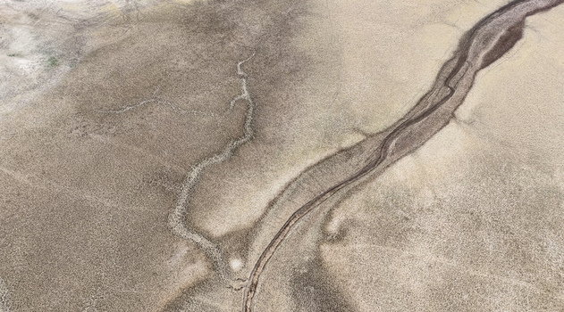 Aerial view of a dry cracked river bed cutting through a parched landscape highlighting the effects of severe drought in Bloemhof North West South Africa. Aerial view of a dry cracked river bed cutting through a parched landscape highlighting the effects of severe drought in Bloemhof North West South Africa.