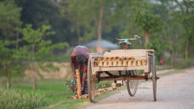 View of a man arranging clay pots on a wooden cart Bangladesh. View of a man arranging clay pots on a wooden cart Bangladesh.