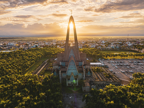 Aerial view of Basilica Nuestra Senora De La Altagracia surrounded by lush greenery and a parking lot at sunset in Higuey La Altagracia Province Dominican Republic. Aerial view of Basilica Nuestra Senora De La Altagracia surrounded by lush greenery and a parking lot at sunset in Higuey La Altagracia Province Dominican Republic.