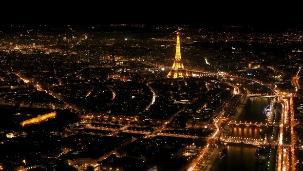 Aerial view of the illuminated Eiffel Tower standing amidst glowing city lights at night with the Seine River winding through the urban landscape of Paris Ile de France France. Aerial view of the illuminated Eiffel Tower standing amidst glowing city lights at night with the Seine River winding through the urban landscape of Paris Ile de France France.