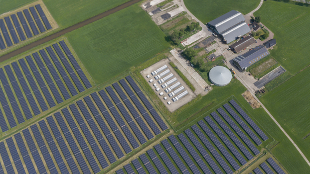 Aerial view of a large solar farm with rows of photovoltaic panels situated next to traditional farm buildings and green fields in Wanneperveen Overijssel Netherlands. Aerial view of a large solar farm with rows of photovoltaic panels situated next to traditional farm buildings and green fields in Wanneperveen Overijssel Netherlands.