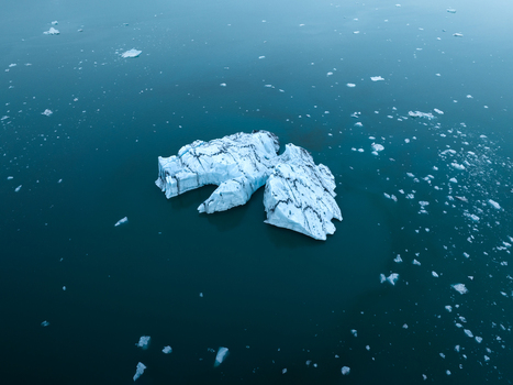 Aerial view of a serene iceberg drifts in the glacial lagoon its icy facade reflecting the cool calm waters Jokulsarlon Sveitarfélagið Hornafjörður Iceland. Aerial view of a serene iceberg drifts in the glacial lagoon its icy facade reflecting the cool calm waters Jokulsarlon Sveitarfélagið Hornafjörður Iceland.