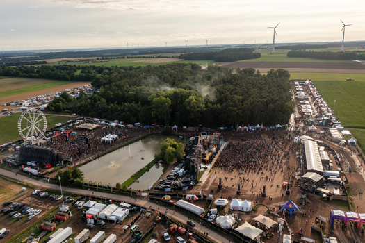 Herzogenaurach Germany 27 July 2025 Aerial view of Open Beatz Festival with stages a Ferris wheel and crowds of people surrounded by forest and wind turbines. Herzogenaurach Germany 27 July 2025 Aerial view of Open Beatz Festival with stages a Ferris wheel and crowds of people surrounded by forest and wind turbines.