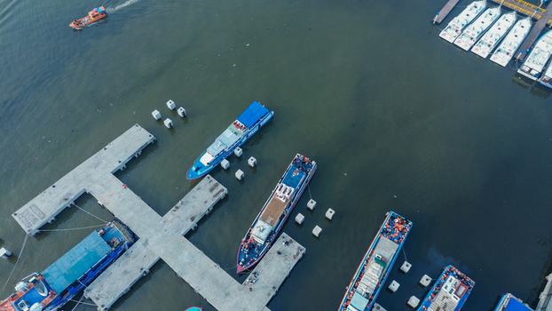 Aerial view of Port of Kali Adem with wooden fishing boats docked at the pier calm waters and industrial harbor infrastructure in Kecamatan Penjaringan Daerah Khusus Ibukota Indonesia. Aerial view of Port of Kali Adem with wooden fishing boats docked at the pier calm waters and industrial harbor infrastructure in Kecamatan Penjaringan Daerah Khusus Ibukota Indonesia.