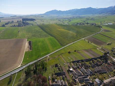Aerial view of lush green agricultural fields and a rural road leading towards the mountains near a small village in Partizanska Lupca Zilina Region Slovakia.