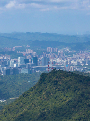 Aerial view of the dense urban skyline of Taipei City with modern skyscrapers and residential buildings nestled against lush green hills under a clear blue sky in Taipei City Taiwan. Aerial view of the dense urban skyline of Taipei City with modern skyscrapers and residential buildings nestled against lush green hills under a clear blue sky in Taipei City Taiwan.