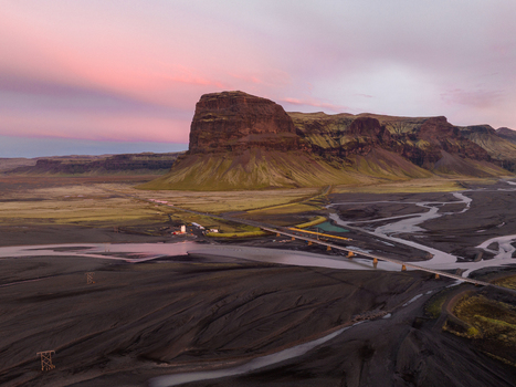Aerial view of rugged mountains meet stark black sand flats bisected by braided glacial rivers under a pastel sky Skaftafell Skaftárhreppur Iceland. Aerial view of rugged mountains meet stark black sand flats bisected by braided glacial rivers under a pastel sky Skaftafell Skaftárhreppur Iceland.